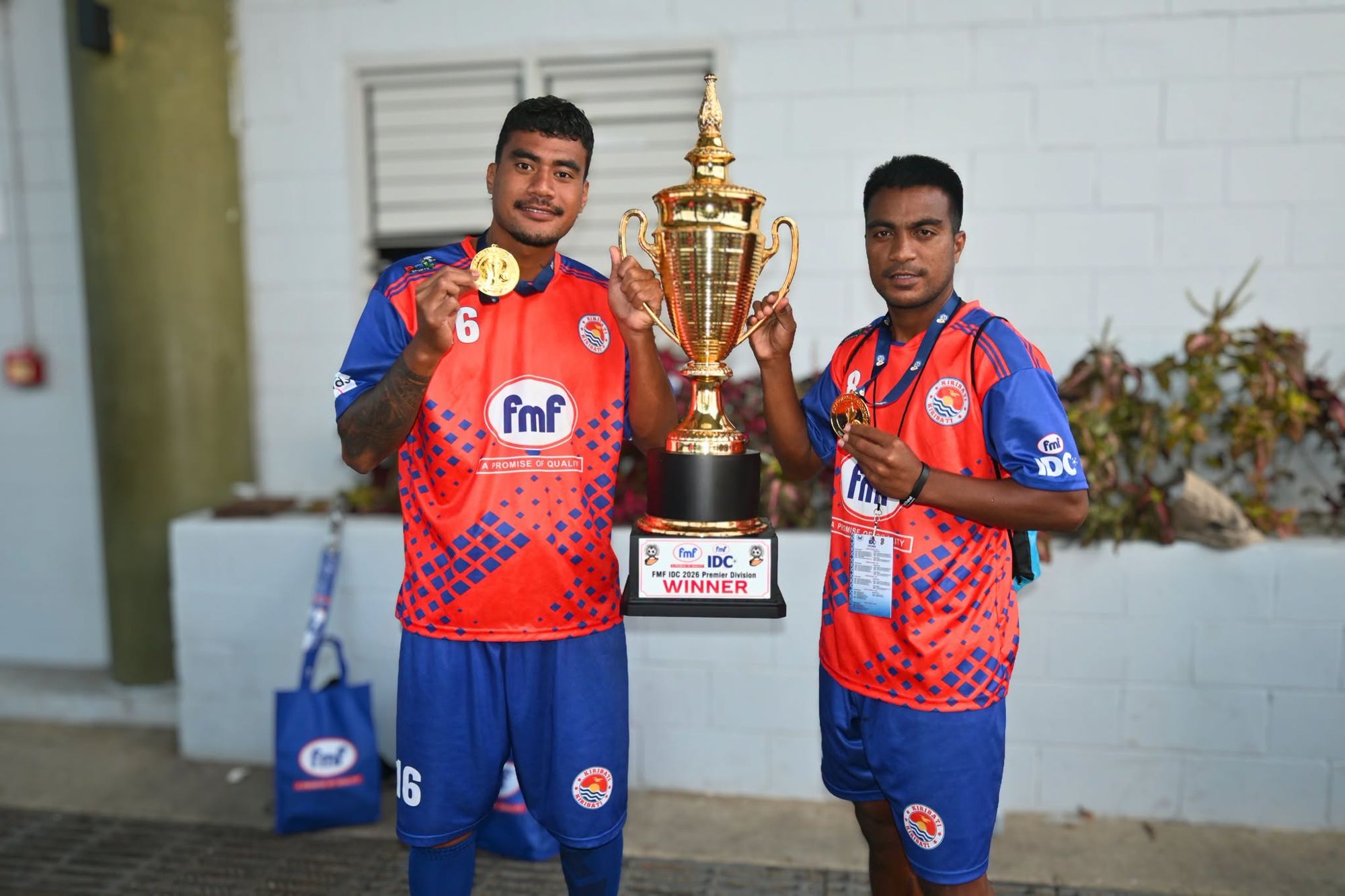 Two Kiribati players with their winners’ medals and the FMF IDC 2026 Premier Division trophy
